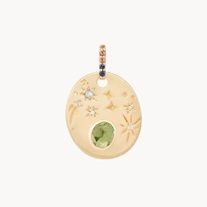 Detalle de colgante ovalado bañado en oro de 14K con gema verde y motivos de estrellas