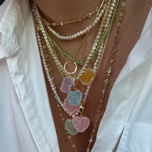 Detalle de collares dorados con colgantes de corazones de resina coloridos y perlas