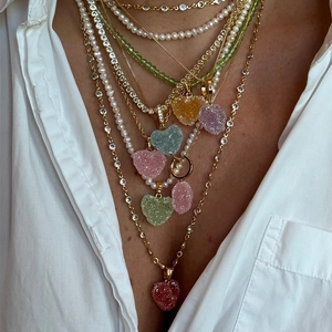 Detalle de collares de perlas con colgantes de corazones sobre una camisa blanca