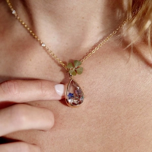 Collar dorado con colgante de gota de agua, flores secas de colores y amuleto de trébol