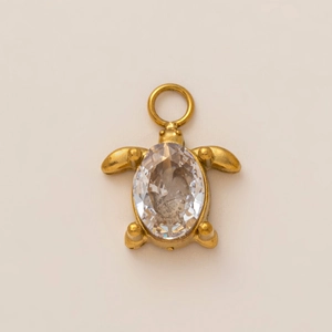 Macro detail of a 18K gold-plated turtle pendant with a faceted oval zircon crystal