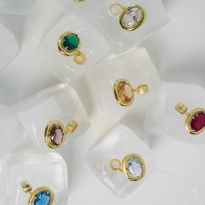 Polished 18K gold plated stainless steel birthstone pendants on a clear ice background