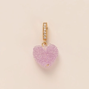 Macro shot of purple crystal heart charm with gold bail and clear zircon inlay