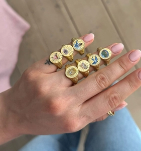 Detailed close-up of gold-plated signet rings with colorful enamel lion and heart patterns