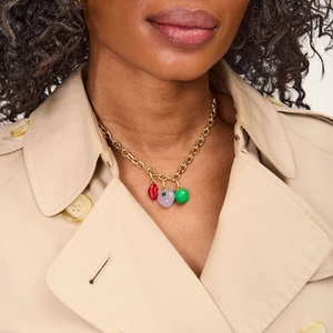 Close-up of chunky gold chain necklace with red lips and purple heart charms on model