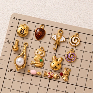 Assorted DIY 18K gold plated charms with animals and pearls on a scale mat