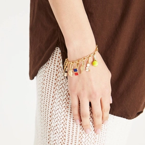 Golden charm bracelet with tennis ball and OUI pendant for women in a sporty fashion style