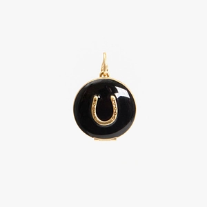 Detail of round gold pendant with black enamel finish and lucky horseshoe motif charms
