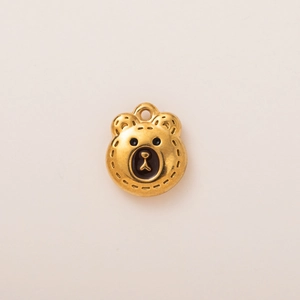 Close-up of golden bear charm with fine stitch texture and enamel eye details