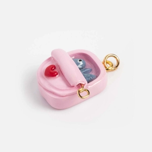 Macro shot of 18K gold plated pink backpack charm with blue cartoon character and red heart