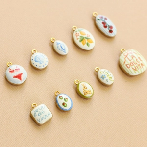 Dettaglio di ciondoli in ceramica placcati oro 18K con motivi di frutta e conchiglie