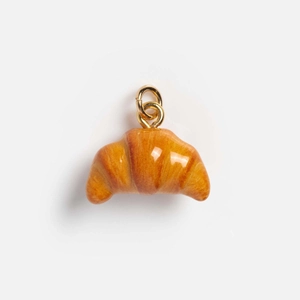 Macro detail of high-simulation croissant pendant with glossy finish and gold metal loop