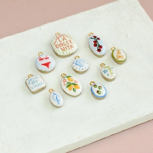 Dettaglio di ciondoli in ceramica placcati oro 18K con motivi mediterranei dipinti