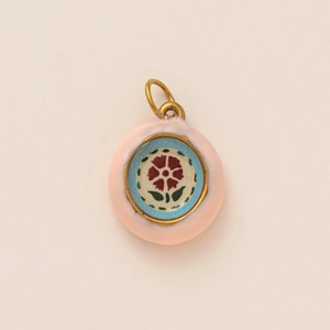 Detail of vintage round charm with pink enamel and floral mosaic inlay in gold frame