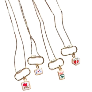 Four gold stainless steel necklaces with carabiner charms including tulip and strawberry