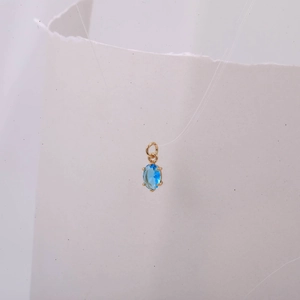 Detalle macro del colgante de piedra azul ovalada con engaste dorado de cuatro garras