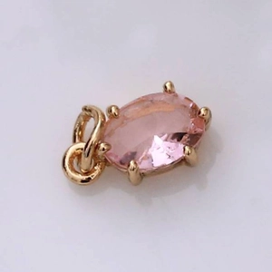 Vista macro de un colgante ovalado con gema rosa y montura de cuatro garras doradas