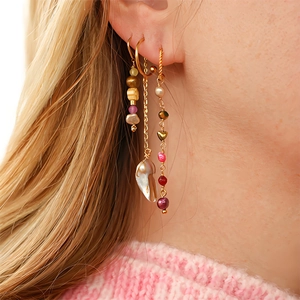 Détail de boucles d'oreilles bohèmes dorées avec perles baroques et perles colorées