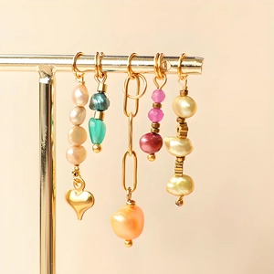 Détail de breloques cœur et soleil avec perles baroques et placage en or 18 carats
