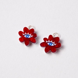 Detail of red flower charms with blue eye pattern and gold loops for jewelry DIY