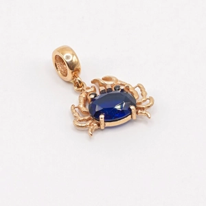 Détail d'un pendentif crabe doré serti d'une grande pierre précieuse bleu foncé