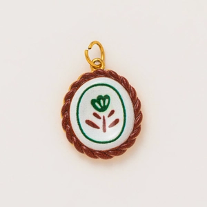 Detail of 18K gold plated oval pendant with green flower enamel and twisted rope border