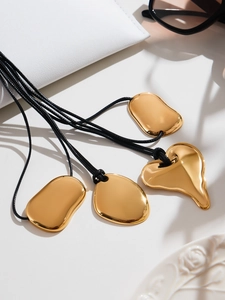 Détail de pendentifs cœur et galets dorés sur cordons noirs avec accessoires de luxe chics