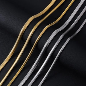 Detailed view of flat snake chains in gold and silver finish on leather texture