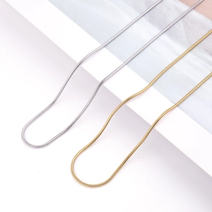 Detailed close-up of gold and silver stainless steel snake chains on a white display