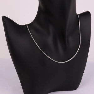 Detail of round silver stainless steel snake bone chain necklace on black bust stand
