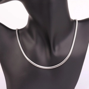 Close-up of a silver flat herringbone snake chain necklace on a black mannequin