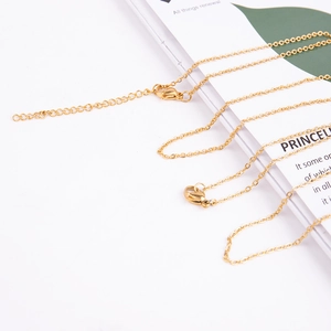 Close-up of golden stainless steel cross chain with lobster clasp and teardrop extension