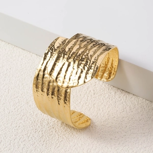 Detailed macro view of 18K gold-plated wide open cuff with hammered metal texture
