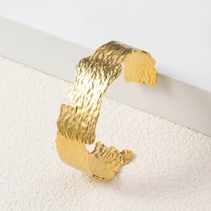 Detailed close-up of 18K gold plated wide cuff bracelet with textured hammered metal finish