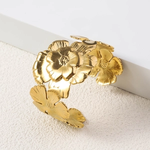 Macro detail of a 18K gold plated flower-shaped open cuff bracelet with embossed petals