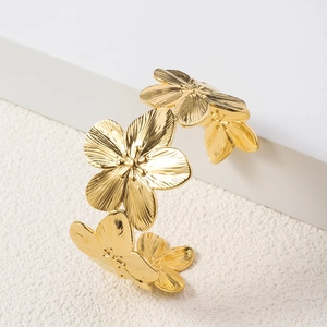 Macro view of gold flower-shaped stainless steel bracelet with brushed metal texture