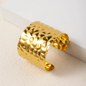 Detailed macro view of gold-plated wide hammered texture cuff bangle bracelet