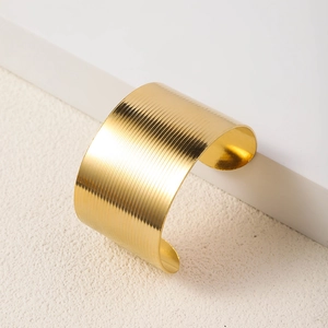 Detailed close-up of a wide gold-plated stainless steel cuff with ribbed texture finish