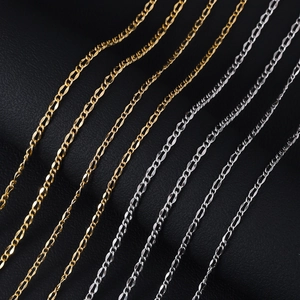 Close-up of gold and silver Figaro chains in three widths on black leather surface