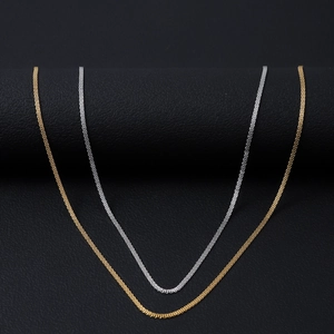 Detail van minimalistische mesh kettingen in goud en zilver op zwart lederen ondergrond