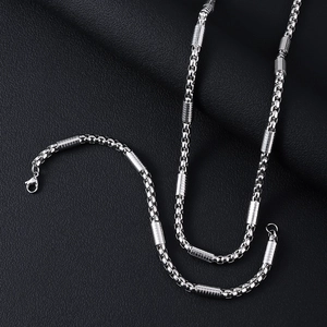 Close-up of silver box chain necklace with cylindrical textured accents on black leather