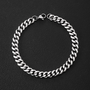 Detail shot of a silver Cuban link bracelet with lobster clasp on black leather background