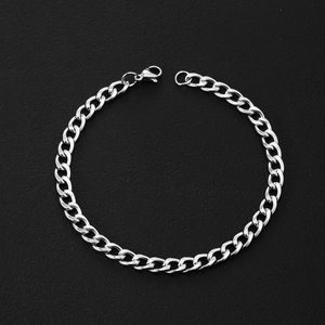Macro view of a polished stainless steel Cuban link bracelet with a lobster clasp