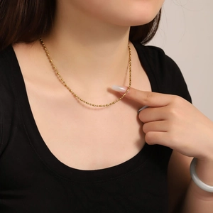 Detail einer 18K vergoldeten Perlenkette aus Edelstahl am Dekolleté einer Frau