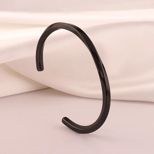 Macro shot of polished black stainless steel Mobius cuff bracelet on silk fabric