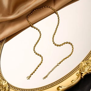 Detail of 18K gold-plated bead chain with lobster clasp on a vintage mirror surface