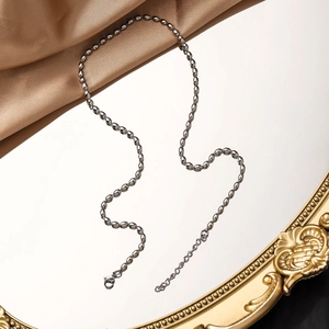 Detailed shot of silver bead chain necklace with lobster clasp on vintage mirror
