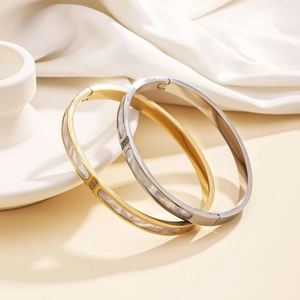 Macro detail of gold and silver steel bangles featuring white shell inlay and crystals