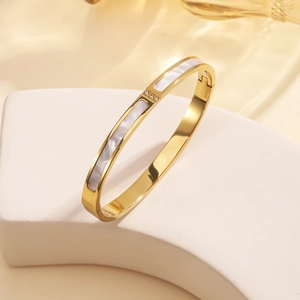 Macro shot of 18K gold plated steel bangle with shell inlay and three small rhinestones