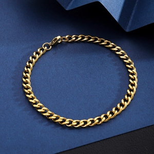 Close-up of 18K gold plated Cuban link bracelet with lobster clasp on blue textured background